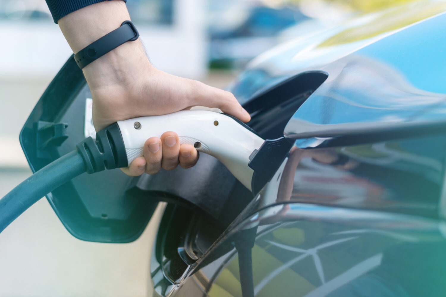 Man plugging in charger into an electric car at charge station